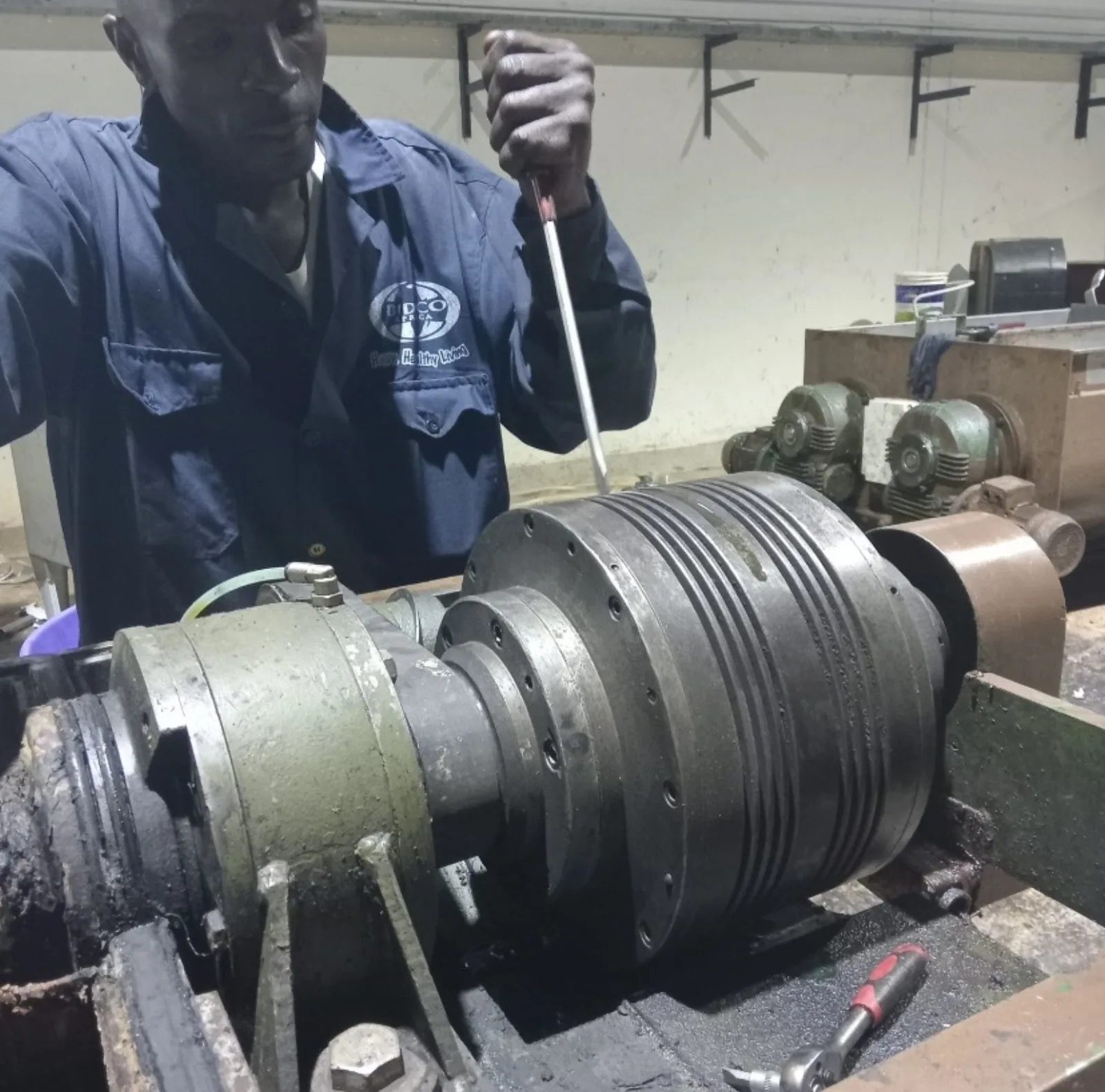 AMAT technician servicing a high-torque industrial electric motor and drive mechanism